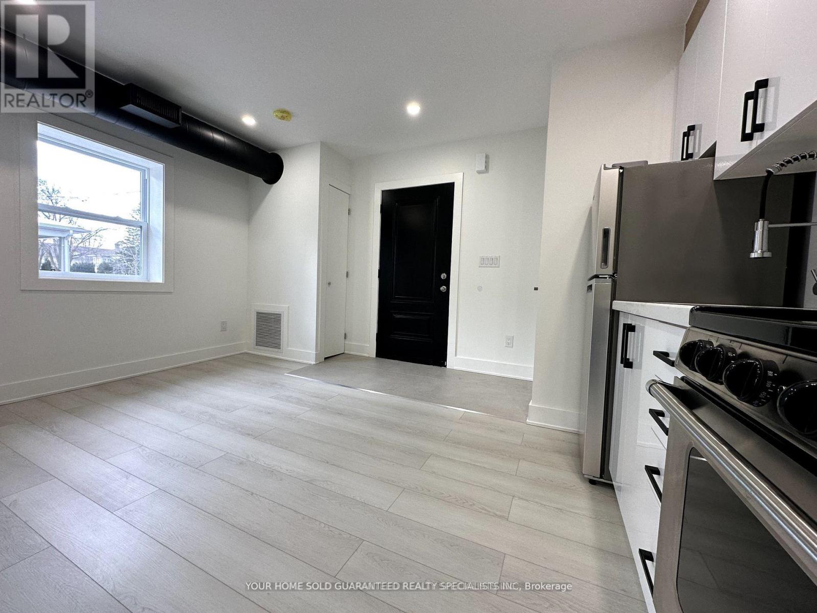A kitchen with a stove top oven and a black door.