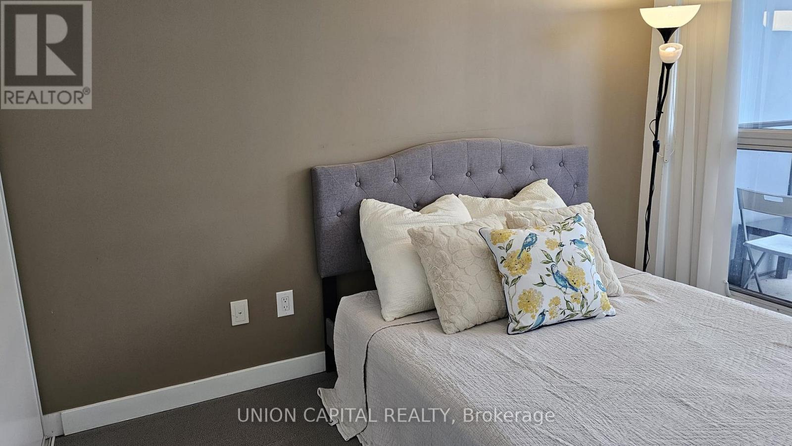 A bedroom with a bed, pillows, and a lamp.