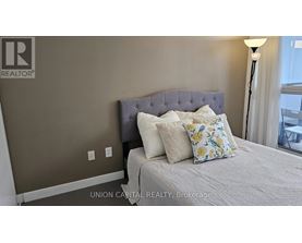 A bedroom with a bed, pillows, and a lamp.