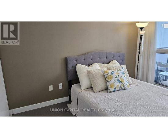 A bedroom with a bed, pillows, and a lamp.