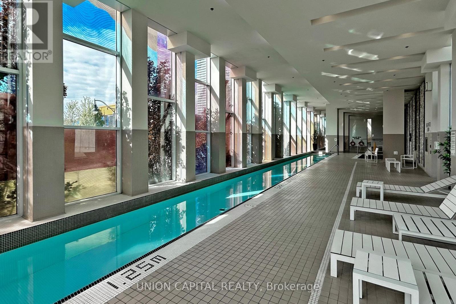 A pool area with a long rectangular pool and benches on the side.