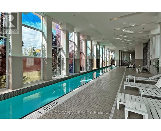 A pool area with a long rectangular pool and benches on the side.