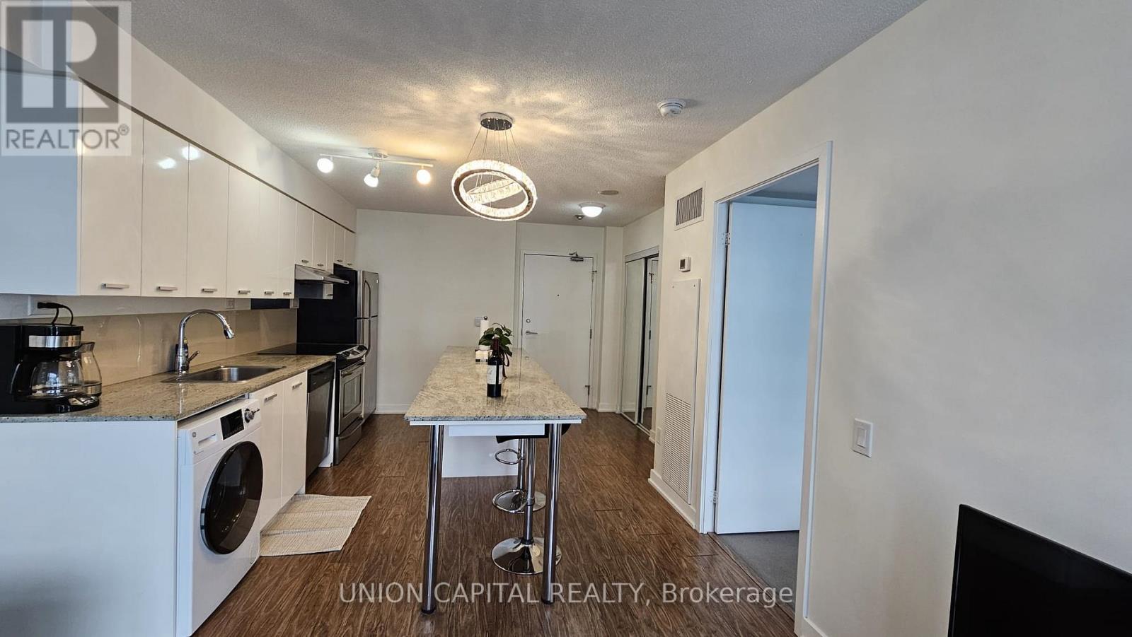 A kitchen with white appliances and a table with a vase of flowers on it.