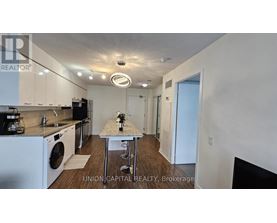 A kitchen with white appliances and a table with a vase of flowers on it.
