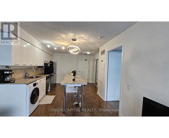 A kitchen with white appliances and a table with a vase of flowers on it.