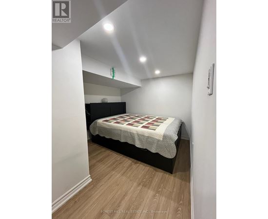 A bedroom with a bed and wooden flooring.