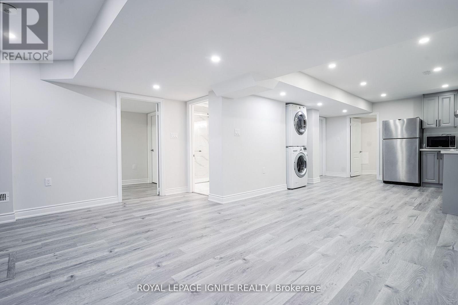 A spacious, empty room with wood flooring and white walls.