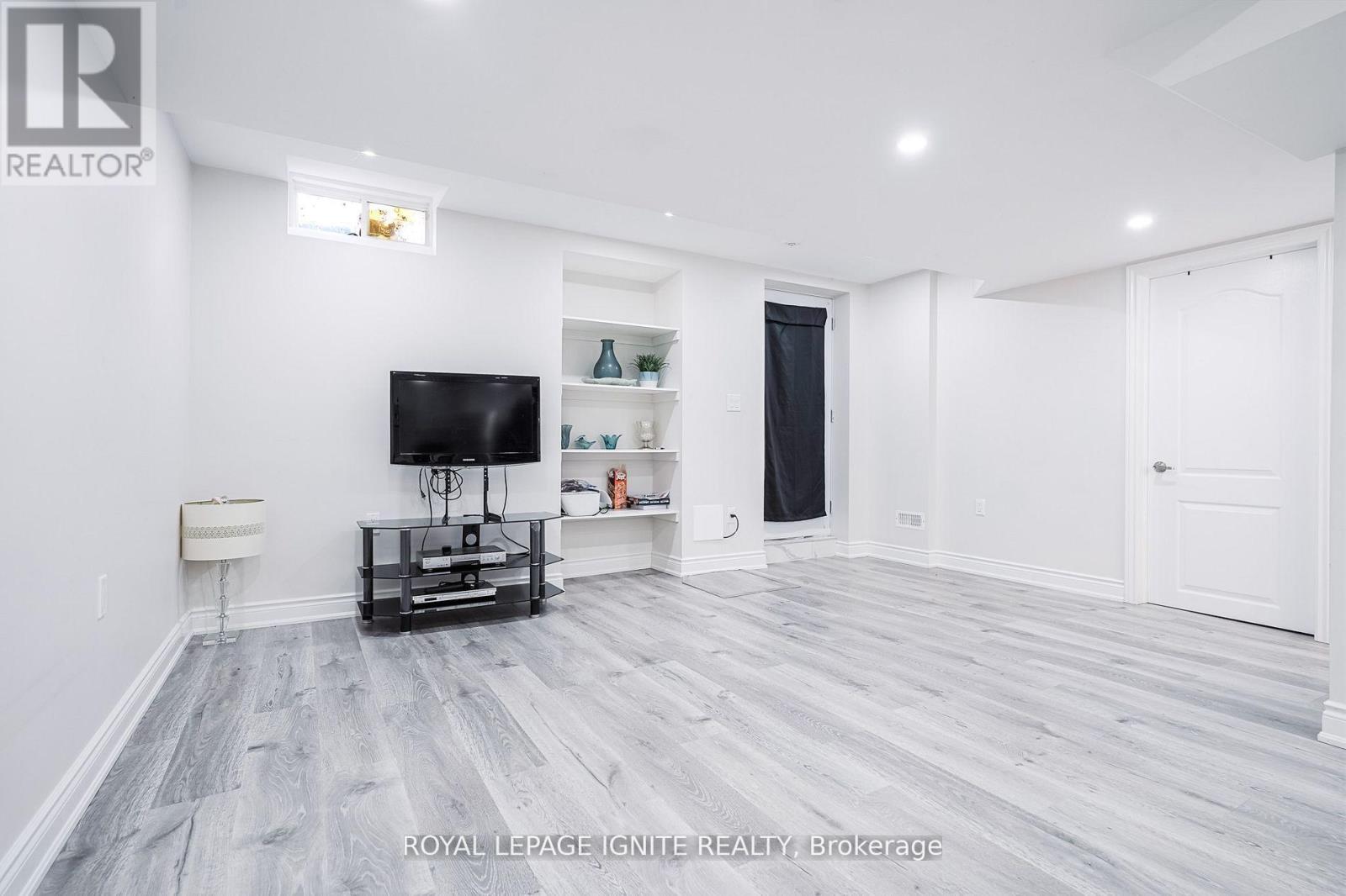 A spacious living room with a grey floor and white walls.