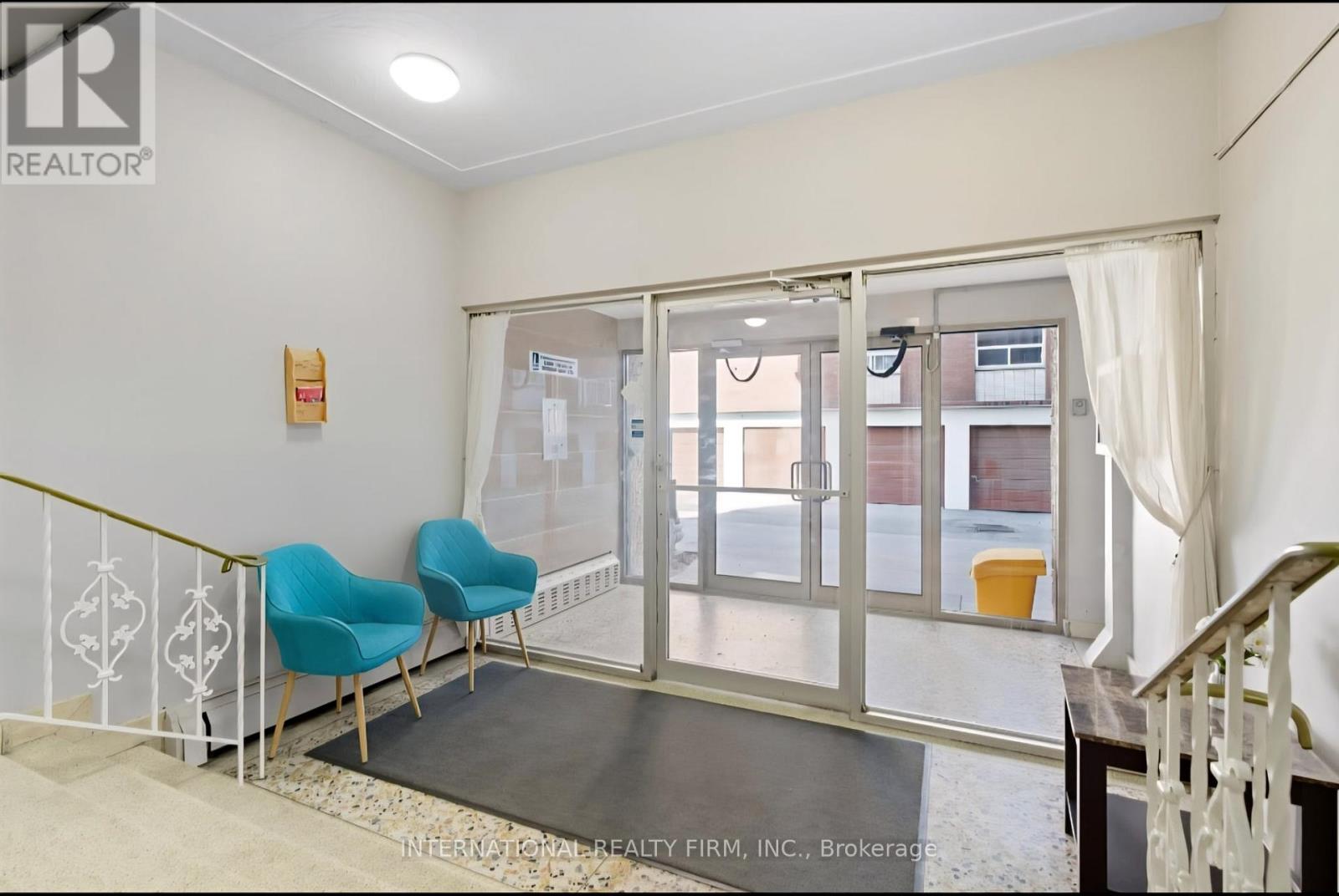 A room with a white wall and a glass door leading to a balcony.