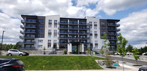 A modern apartment building with a parking lot in front.