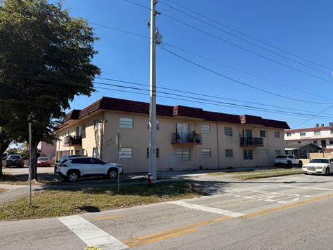 A white car is parked in front of a building with a red roof.