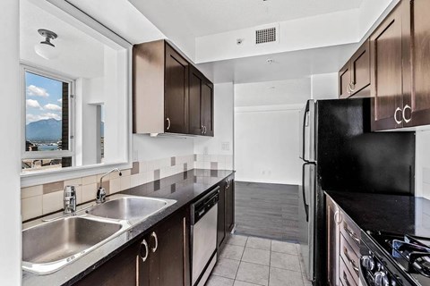 A kitchen with a black refrigerator and stove top oven.