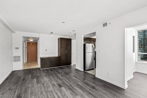 A spacious room with a wooden floor and a stainless steel refrigerator.