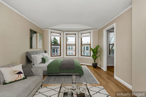 A living room with a grey couch and a green bedspread.