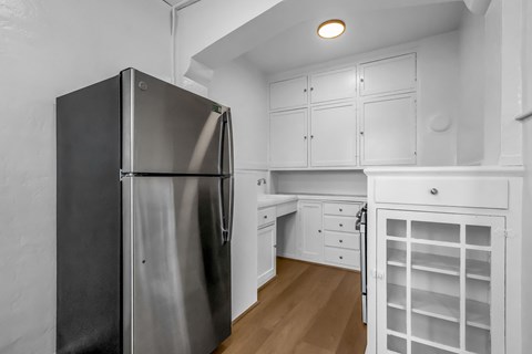 A modern kitchen with a stainless steel refrigerator and white cabinets.