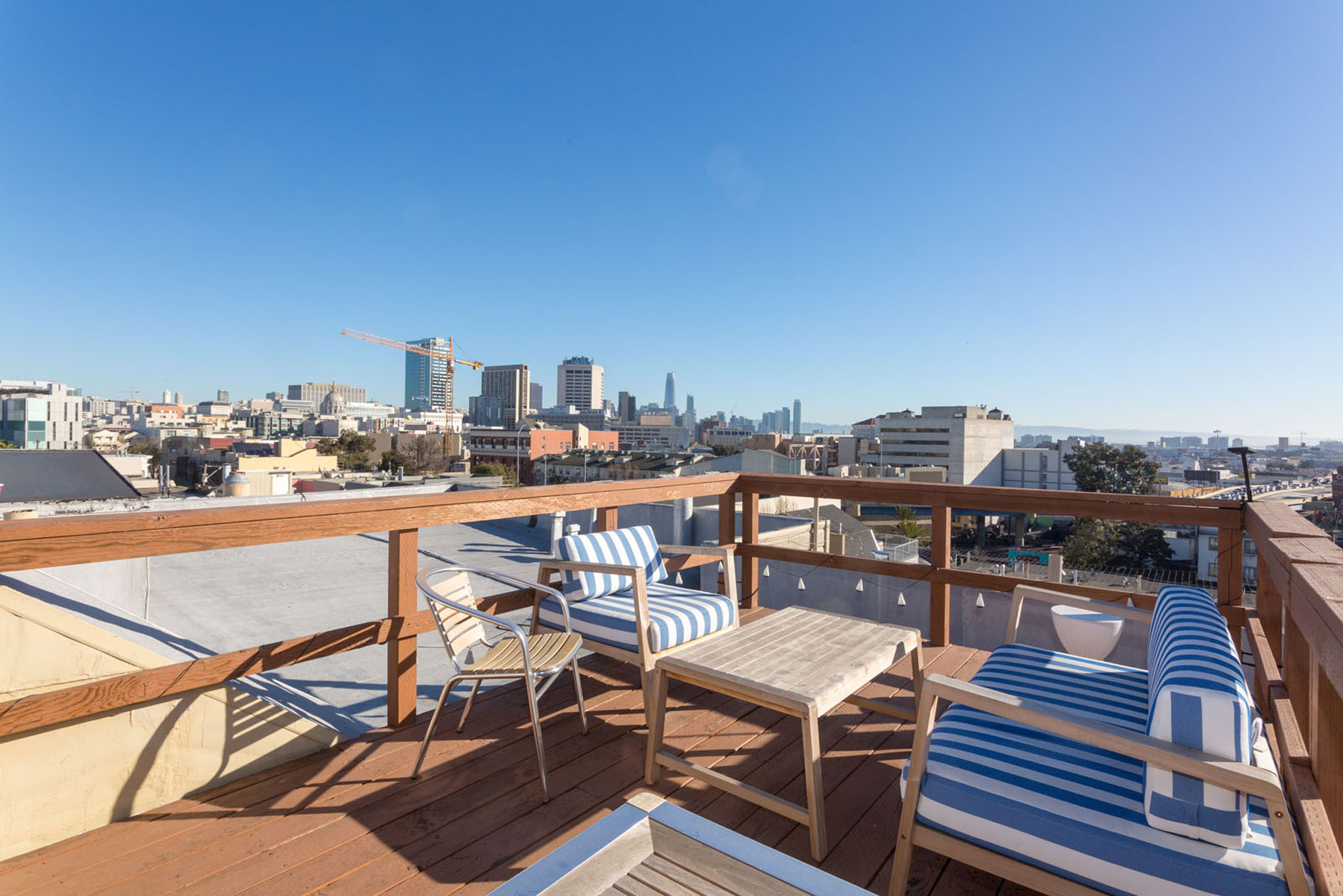 A balcony with striped chairs and a table overlooking a city skyline.