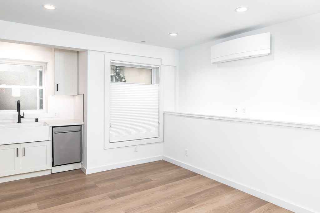A kitchen with white cabinets and a wooden floor.