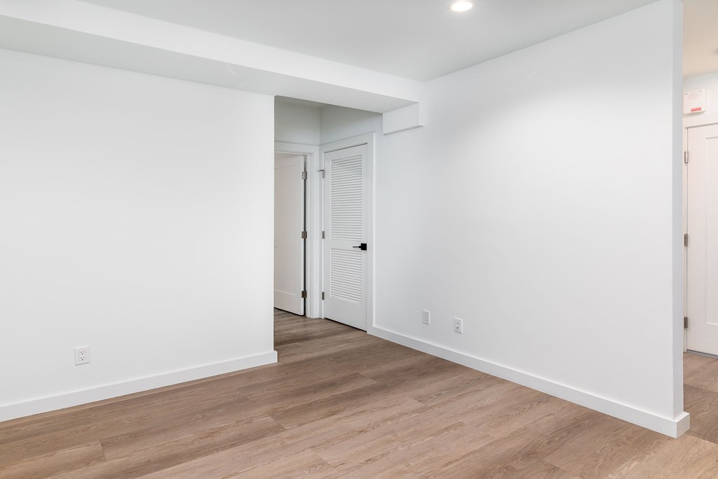 A room with a white door and wooden flooring.