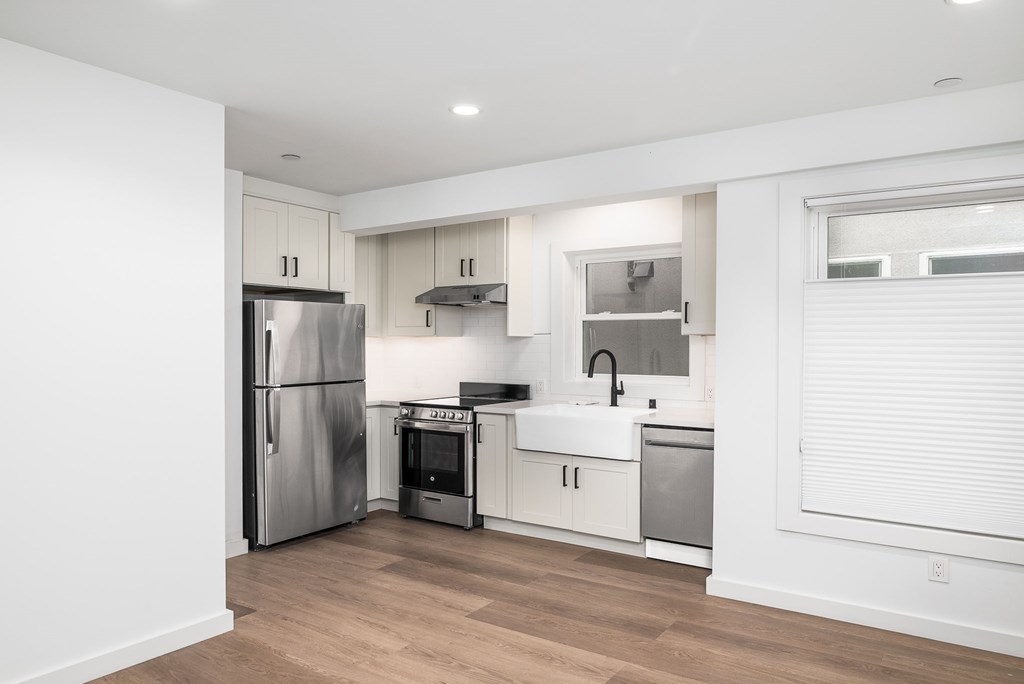 A kitchen with a refrigerator, oven, and sink.