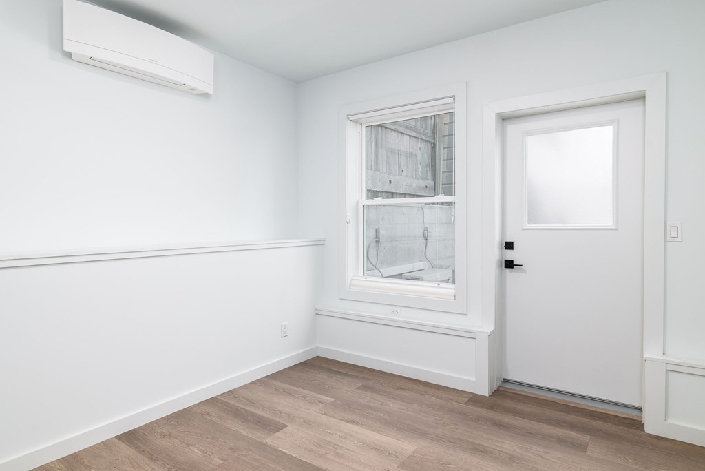 A room with a white door, a window with a white frame, and a white wall with a black switch.