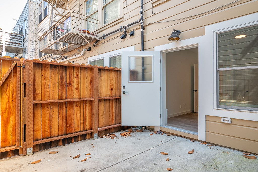 A wooden fence is in front of a tan building.