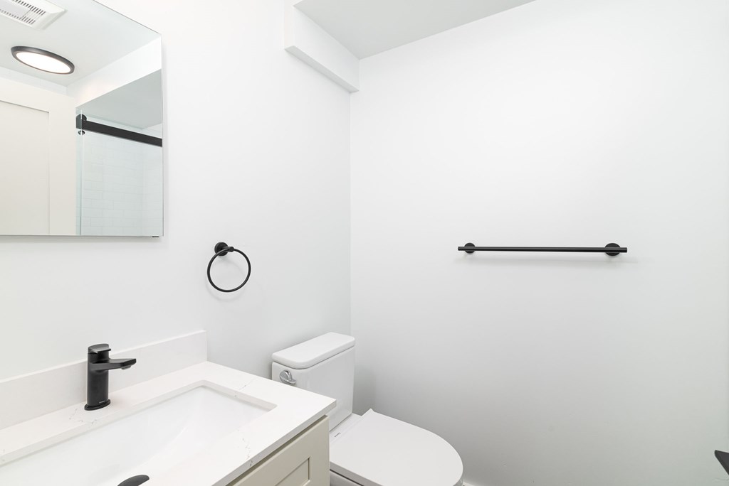 A white bathroom with a toilet, sink, and mirror.