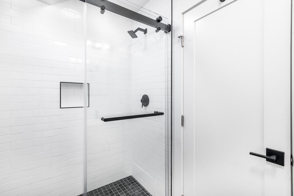 A white bathroom with a glass shower stall and a white door.