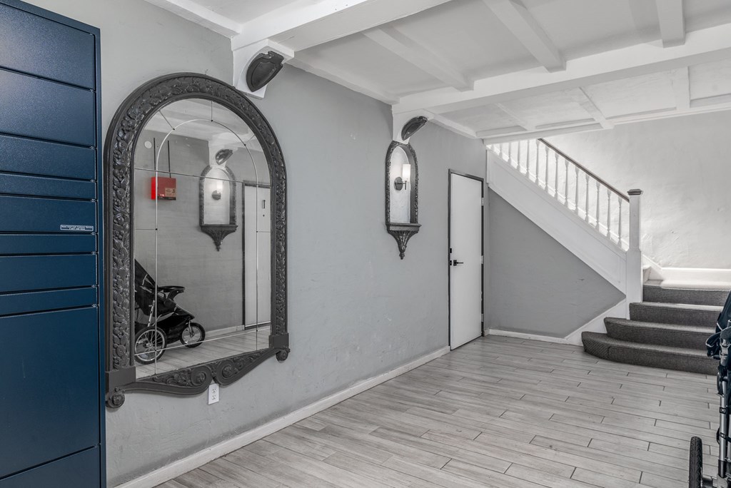 A hallway with a staircase and a mirror on the wall.