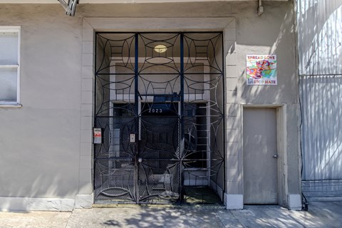 A metal gate with a spider web design is in front of a building.