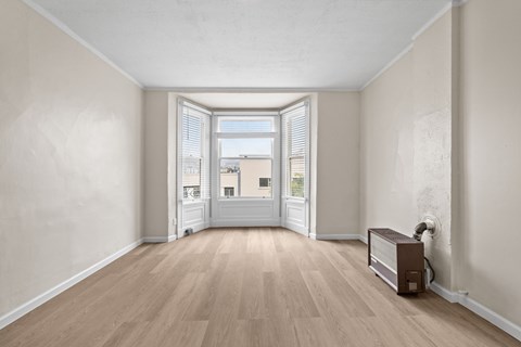 A room with wooden floors and a white door leading to a balcony.