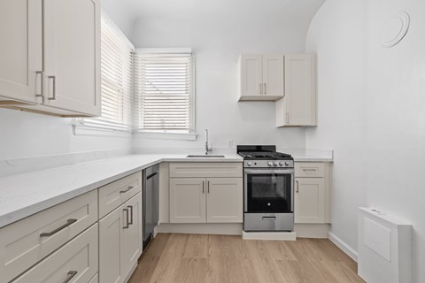 A modern kitchen with a stove top oven and wooden floors.