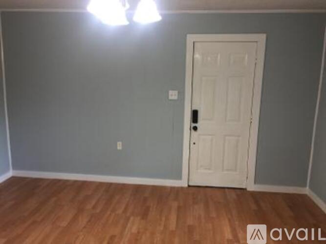 A room with a white door and wooden floor.