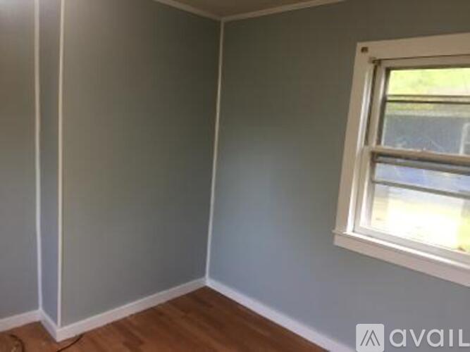 A room with a window and wooden flooring.