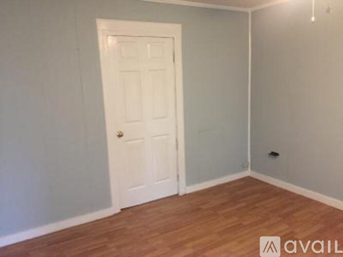 A room with a white door and wooden floor.