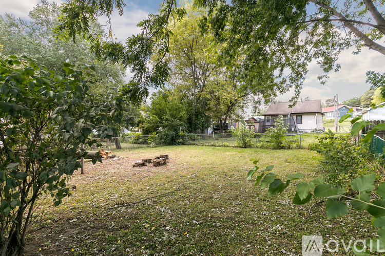 A grassy area with trees and a house in the background.