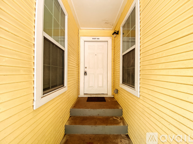 A yellow house with a white door and windows.