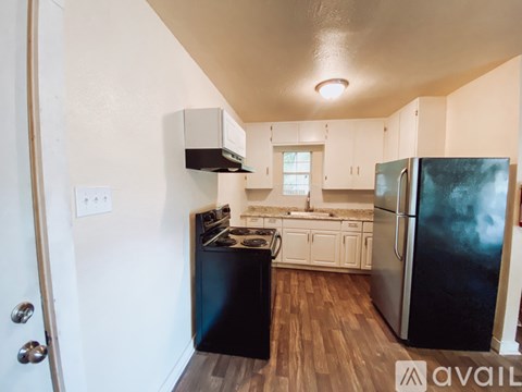A kitchen with black appliances and wooden floors.