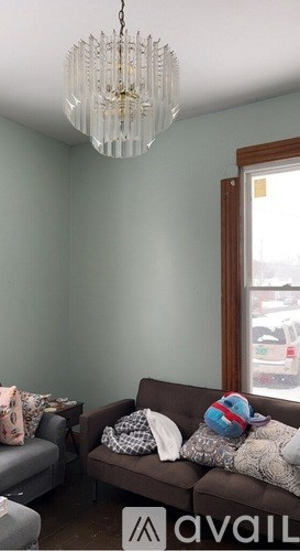 A living room with a grey couch and a chandelier.