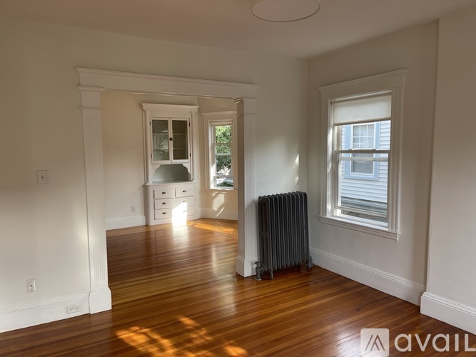 A room with wooden floors and a window with blinds.