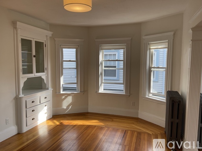A room with wooden floors and three windows.