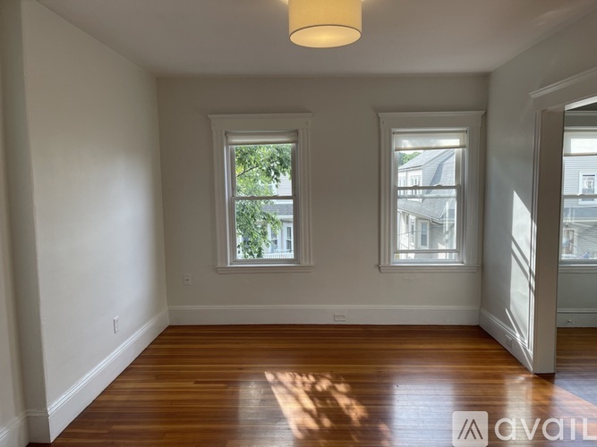 A room with wooden floors and two windows.