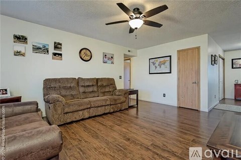 A living room with a brown couch and a ceiling fan.
