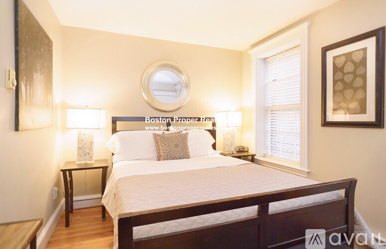 A bedroom with a bed, nightstands, and a mirror on the wall.