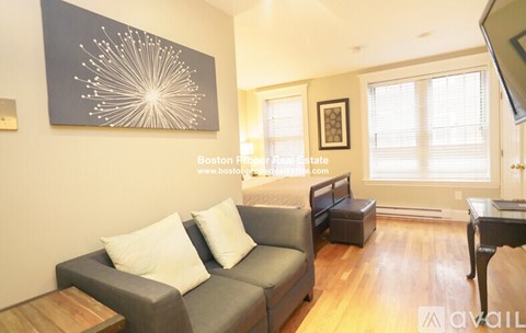 A living room with a grey couch and a large painting on the wall.