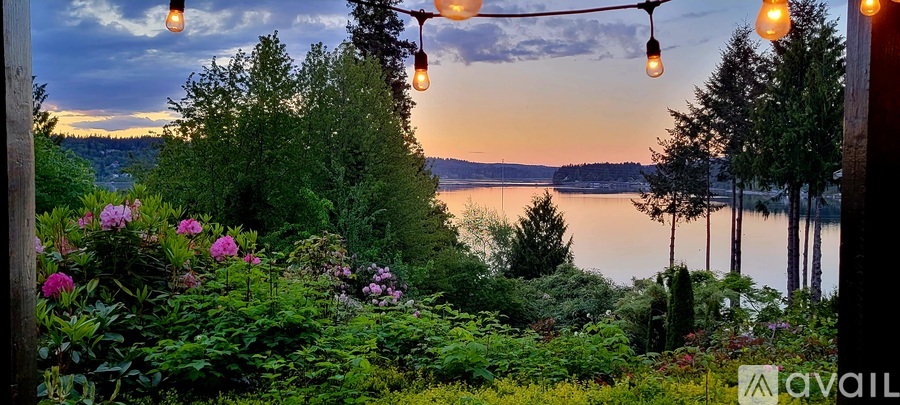 A beautiful garden with flowers and trees overlooking a lake at dusk.