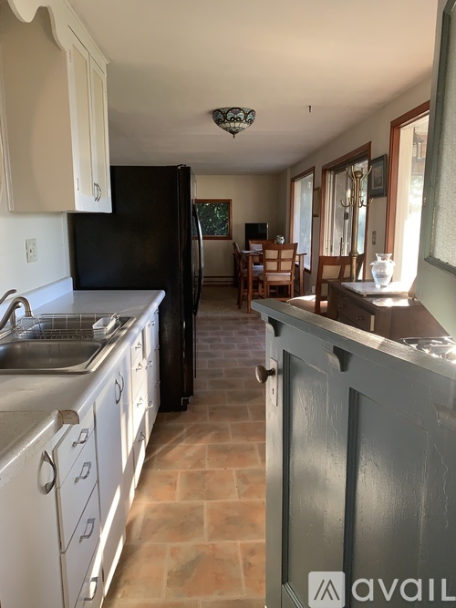 A kitchen with a black refrigerator and white cabinets.