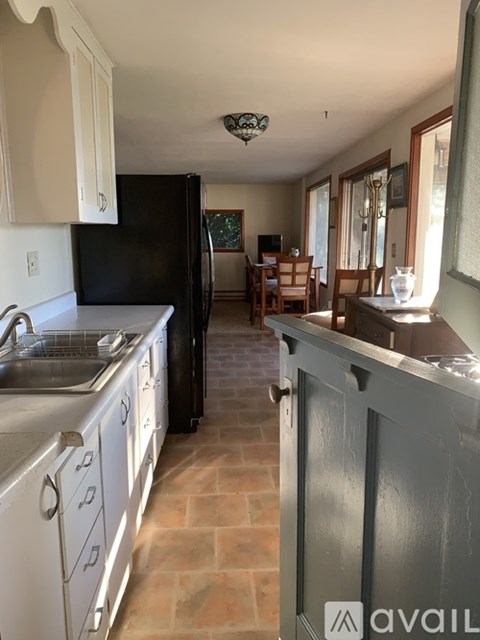 A kitchen with a black refrigerator and white cabinets.