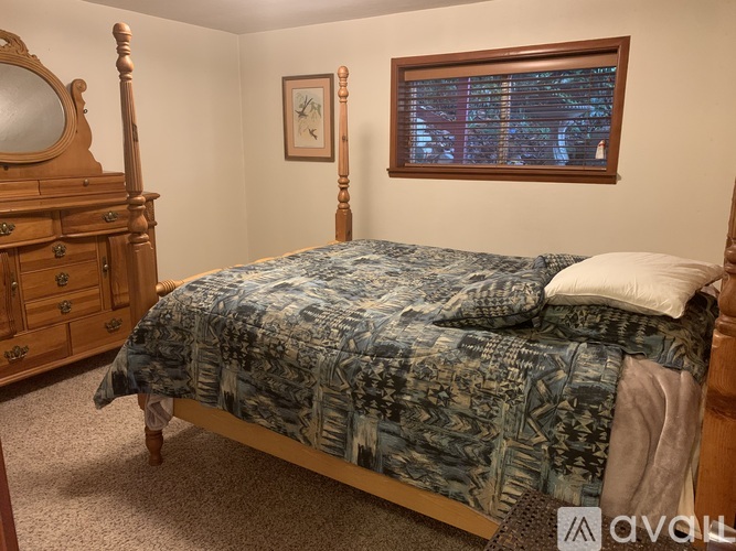 A bedroom with a bed, dresser, and window.