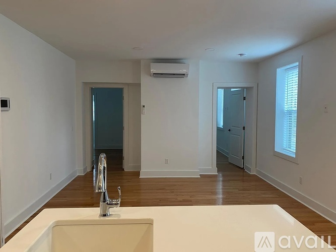 A spacious room with a sink, mirror, and wooden flooring.