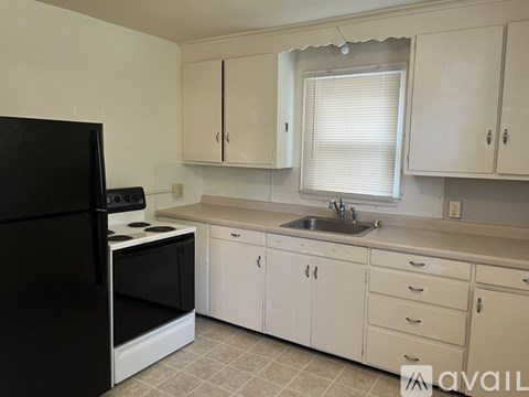 A kitchen with white cabinets and a black refrigerator.
